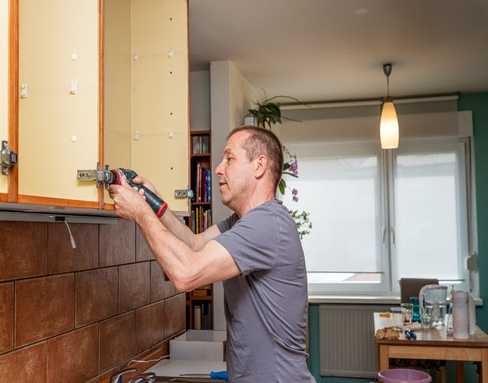 Man removing old kitchen cabinets during home renovation