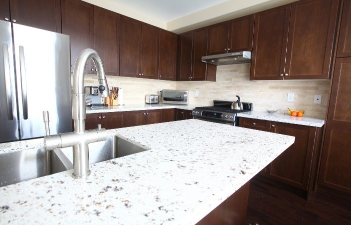 Grey and white color granite kitchen countertop with wooden cabinets in San Diego, CA